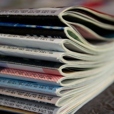 资讯编辑对着双屏逐条比对公开页面信息，屏幕冷光映在专注的侧脸上，桌角贴着写满待办事项的黄色便利贴